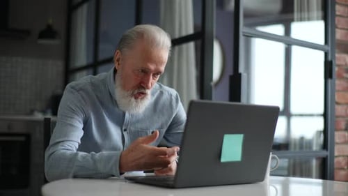 Senior Man on Laptop Video Call in Modern Home