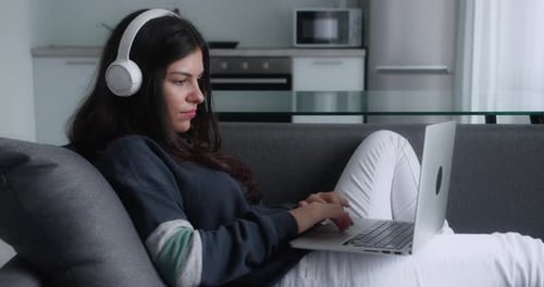 Woman Relaxing on Couch Using Laptop