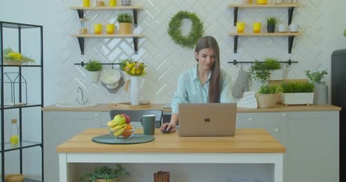 Woman Working on Laptop in Bright Kitchen