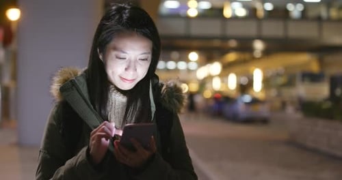 Woman Using Smartphone on City Street at Night
