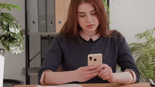 Woman at Desk Using Phone Indoors