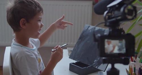 Blogger Boy malt Kunstwerke auf Leinwand und schaut in die Kamera