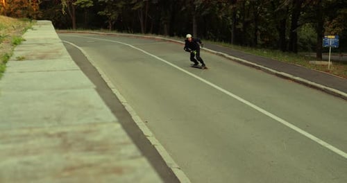 Man Skateboarding Down Quiet Urban Road on Sunny Day