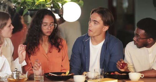 Millennial Friends Enjoing Tasty Meal and Communicating at Cosy Cafe. Young Happy Guys and Girls