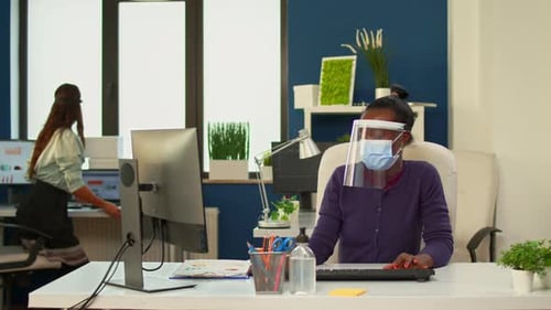 Masked Workers Typing in Shared Office Space