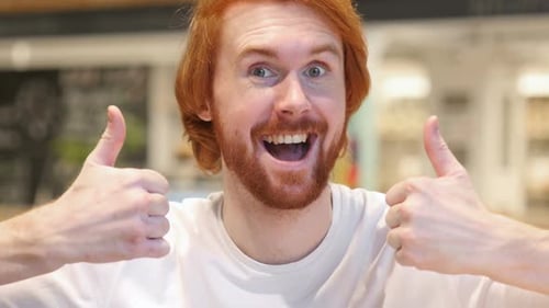Thumbs Up with Both Hands By Redhead Beard Man in Cafe
