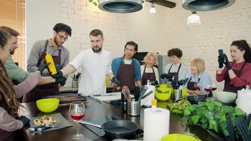 Kochschüler und männlicher Koch kochen gemeinsam Fleischgericht lernen Kulinarisch