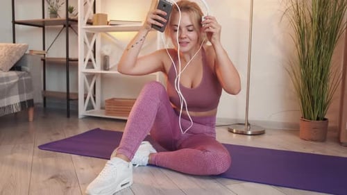 Woman Puts on Headphones Before Workout at Home