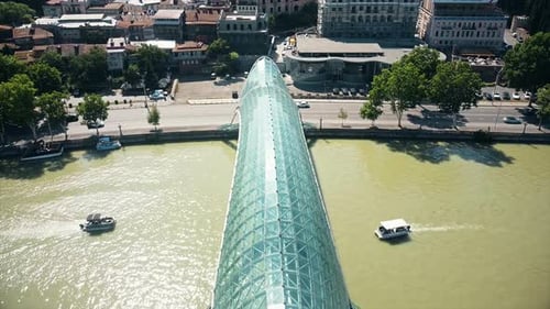 Aerial drone view of Tbilisi, Georgia. Kura river with a modern bridge over it, a lot of greenery, f