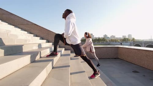 Athletic Pair Stretching in City Park on Sunny Day