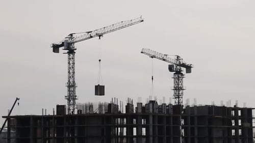 Silhouettes of Construction Cranes Working