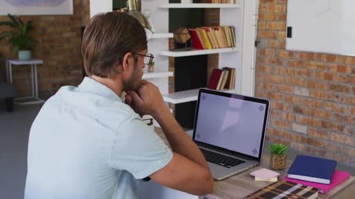 Caucasian male teacher having a videocall on laptop in the classroom at school