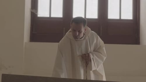 Priest in White Alb Praying in Church