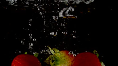 Closeup of fresh and healthy strawberries falling into clear water with big splash
