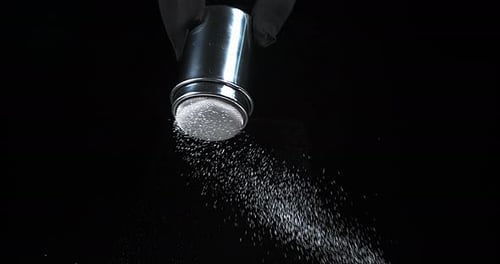 Powder Being Sifted with Metal Sifter on Black Backdrop