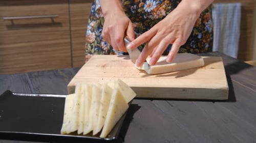 Woman Cuts Fresh Cheese on Board in Kitchen