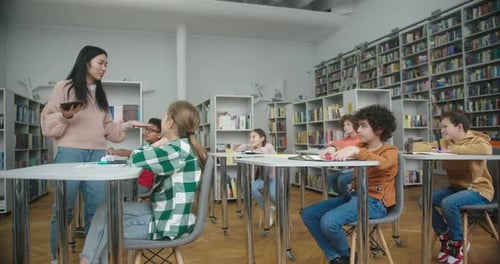 Asiatische Lehrerin erklärt Schulkindern das Thema in der Bibliothek