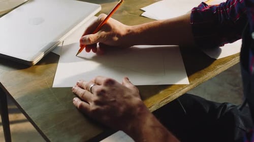 Man Drawing on Paper at Workplace Desk