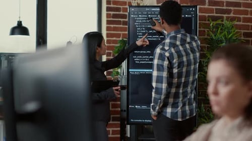 System Developers Analyzing Code on Wall Screen Tv Looking for Errors Comparing Results on Digital