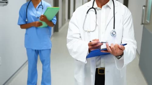 Portrait of smiling doctors with medical reports standing in corridor
