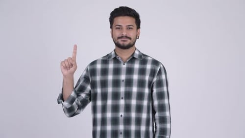 Portrait of Young Happy Bearded Indian Man Pointing Up