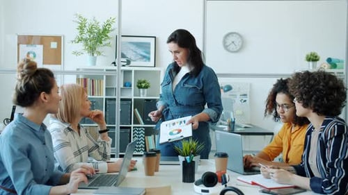 Serious Businesswoman Talking To Multiethnic Group of Employees in Office Room