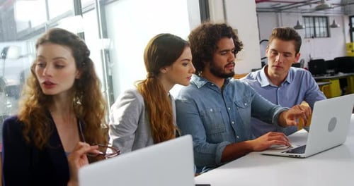 Team Discussing Project on Laptops in Modern Office