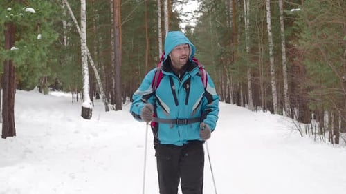 Man with Backpack Walking Throw the Winter Forest
