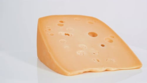 Large slice of semi soft part skim cheese on a white background.