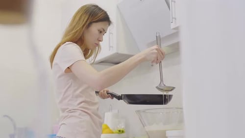 Young Adult Cooking Pancakes in Kitchen