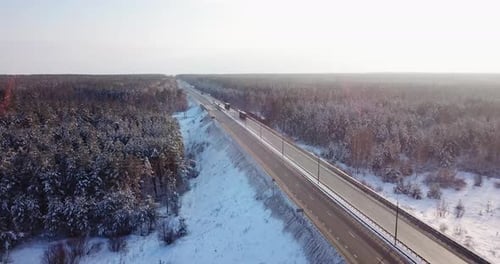 Luftaufnahme einer Autobahnstraße mit Verkehrsautos und Lastwagen auf der Straße im Winter