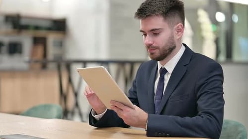 Jeune homme d'affaires utilisant une tablette au bureau