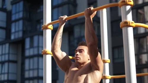Muscular Man Doing Pull-ups on Horizontal Bar. on Workout Area Near House