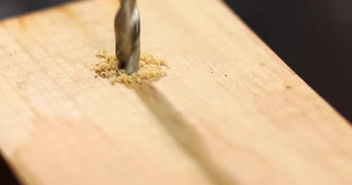 Close up of drilling into wood with screw twisted into place, metal drill bit