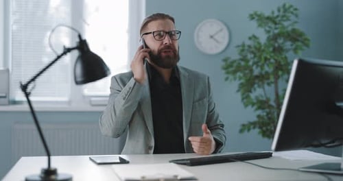 Bearded Man Talking on Phone in Office