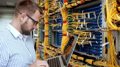 Engineer Working on Laptop in Data Center