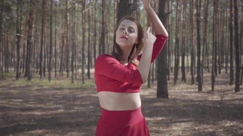 Skill Young Woman in Red Dress Dancing in the Forest. Beautiful Dancer Showing Classic Ballet Poses
