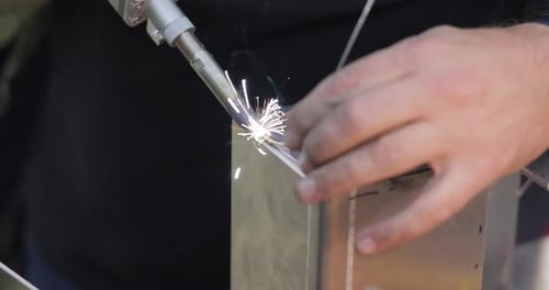 Metalworker Welding a Metal Cube with Sparks