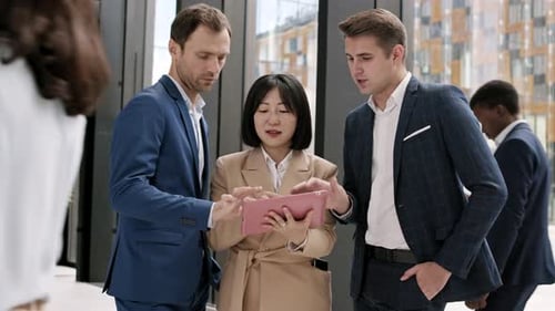 Three Business Colleagues Using Digital Tablet in Office
