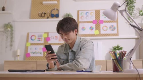 Young Man Using Smartphone at Creative Workspace