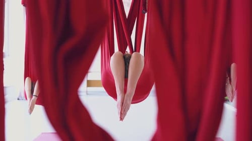 Women Practicing Aerial Yoga in Red Hammocks