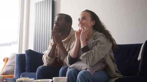 Couple Watches Game, Celebrates with Hug at Home