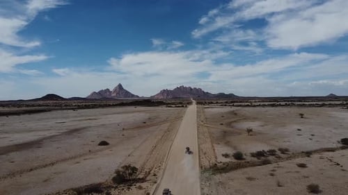 Vista aérea en un largo camino polvoriento a través del desierto hasta las montañas, Namibia