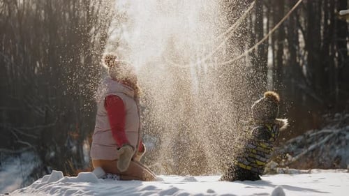 Glückliche Mutter mit kleinem Sohn spielt mit Schnee und wirft es hoch