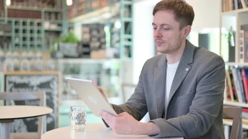 Joven atractivo usando tableta en un café