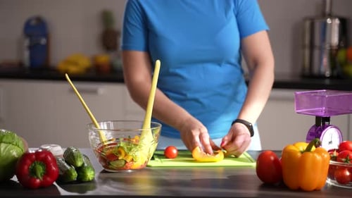 Woman Making Fresh Vegetable Salad in Kitchen