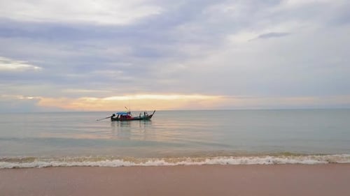 Sunset seen from the beach with a long tail boat on the water