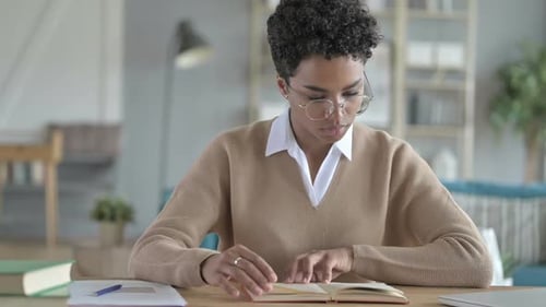 Woman Reads Book at Table Indoors