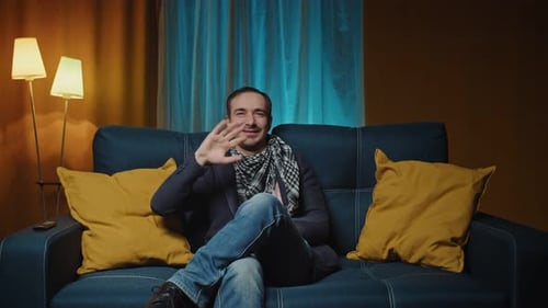 Man on Couch Waving and Smiling