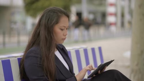 Woman Using Tablet Device on Bench Outdoors